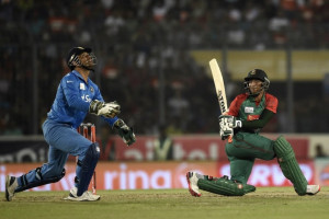 Bangladesh cricketer Shakib Al Hasan (R) plays a shot as the Indian cricket captain Mahendra Singh Dhoni (L) looks on during the Asia Cup T20 cricket tournament final match between Bangladesh and India at the Sher-e-Bangla National Cricket Stadium in Dhaka on March 6, 2016. / AFP / MUNIR UZ ZAMAN
