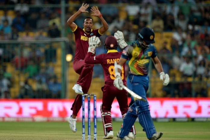 West Indies bowler Samuel Badree (L) celebrates the wicket of Sri Lankan batsman Milinda Siriwardana (R) with wicketkeeper Denesh Ramdin during the World T20 cricket tournament match between West Indies and Sri Lanka at The Chinnaswamy Stadium in Bangalore on March 20, 2016. / AFP / MANJUNATH KIRAN